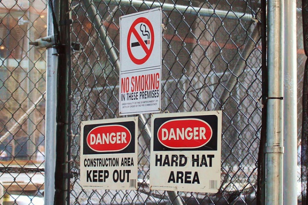 Image of chainlink fence and danger signs to keep out and no smoking
